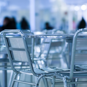 A sesaturated image of cool cafe chairs and tables with people in the background