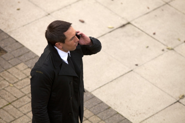 A security guard on the mobile while checking something out, possibly a building