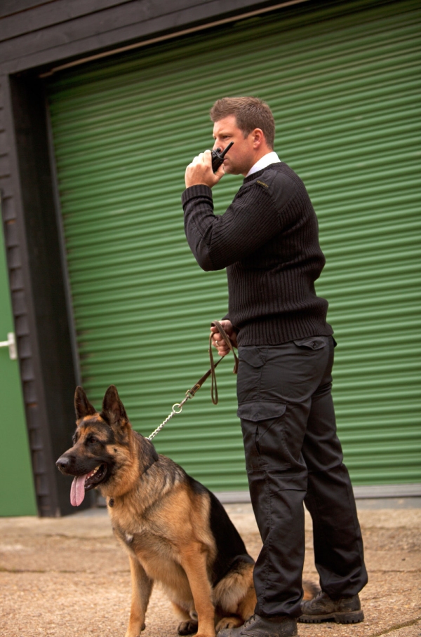 A security guard/dog handler checking out something or someone suspicious