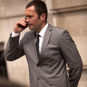 A tense moment as a close protection security officer talks to colleagues on the radio while waiting for important clients to emerge from a building