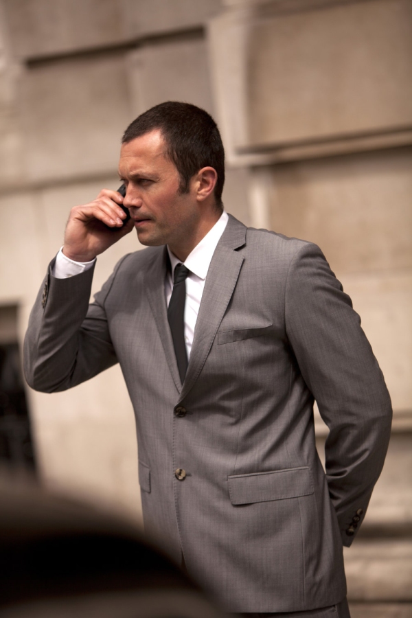 A tense moment as a close protection security officer talks to colleagues on the radio while waiting for important clients to emerge from a building