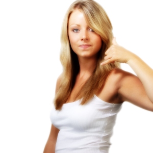 Blonde girl in white looking at camera and making phone gesture