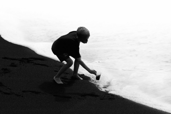 A boy playing in the surf on a black beach