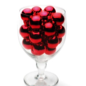 A large wine glass with small red and silver Christmas baubles