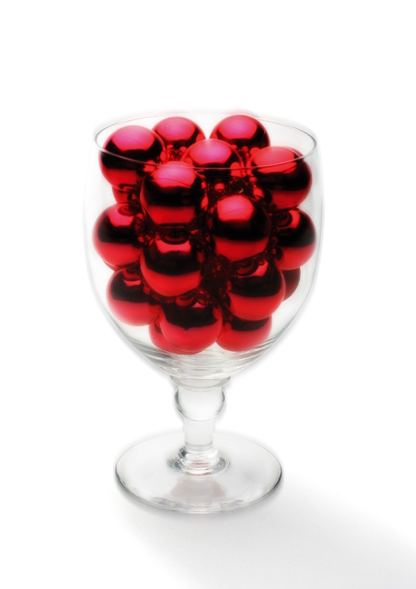 A large wine glass with small red and silver Christmas baubles