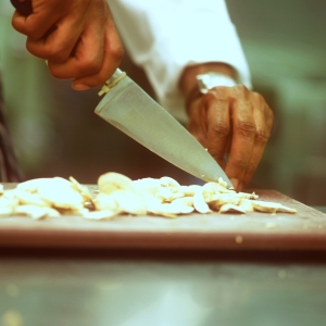 Close up image of chef preparing mushrooms on a wooden chopping board