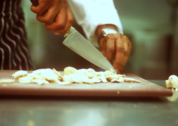 Close up image of chef preparing mushrooms on a wooden chopping board