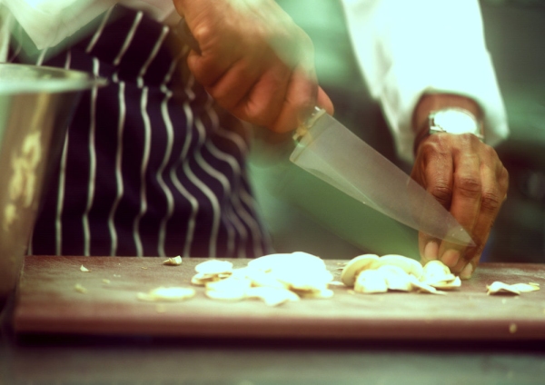 Close up image of chef preparing mushrooms on a wooden chopping board