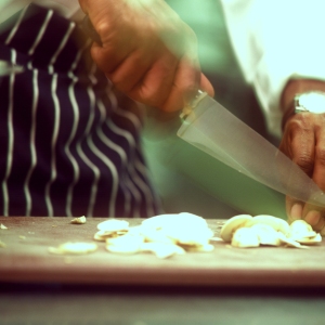 Close up image of chef preparing mushrooms on a wooden chopping board