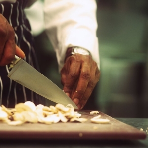 Close up image of chef preparing mushrooms on a wooden chopping board