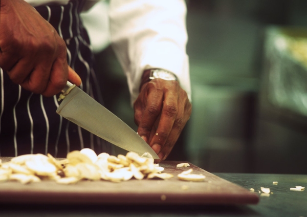 Close up image of chef preparing mushrooms on a wooden chopping board