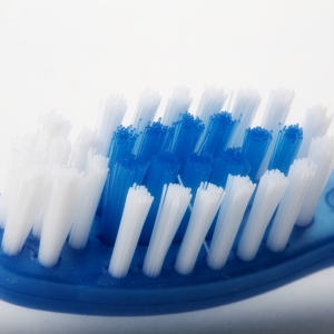 Close up macro view of blue toothbrush with white bristles