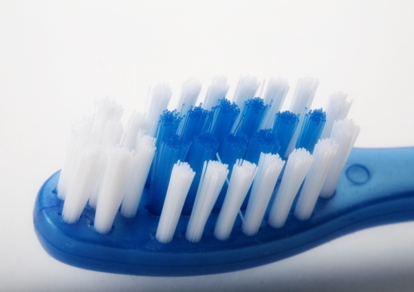 Close up macro view of blue toothbrush with white bristles