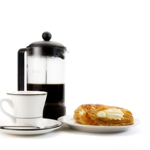 A cup of coffee with some arabica coffee beans, jam and doughnut