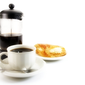 A cup of coffee with some arabica coffee beans, jam and doughnut