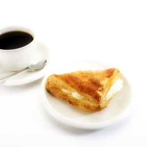 A cup of coffee with a cream filled apple turnover