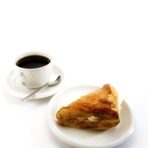 A cup of fresh coffee with a cream filled apple turnover