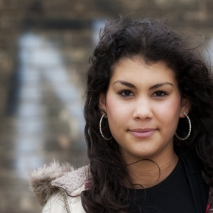 Girl of multi ethnic origin, looking at camera in an urban street background