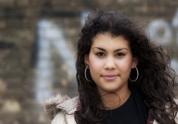 Girl of multi ethnic origin, looking at camera in an urban street background