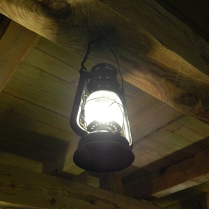 An old fashioned paraffin or oil lamp hanging from the ceiling of a wooden cabin