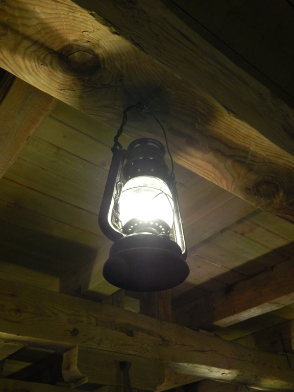 An old fashioned paraffin or oil lamp hanging from the ceiling of a wooden cabin