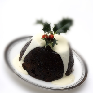 A Christmas pudding with cream and a sprig of holly on top