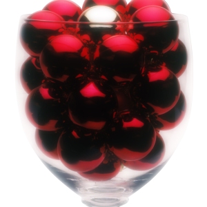 A large wine glass with small red and silver Christmas baubles