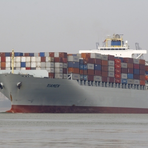 A giant container ship leaving port, stacked high with containers.