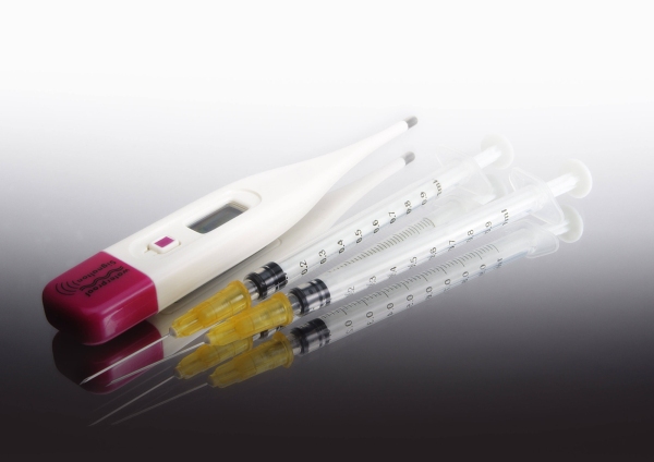 A digital thermometer and two disposable syringes