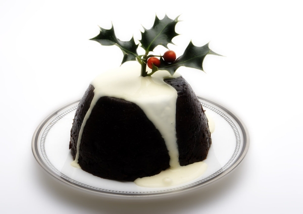 A Christmas pudding with cream and a sprig of holly on top