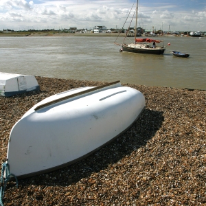 Boats on the shingle and at anchor at Bawdesey in Suffolk