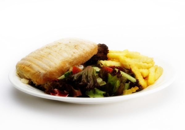 A beefburger and chips with a green salad