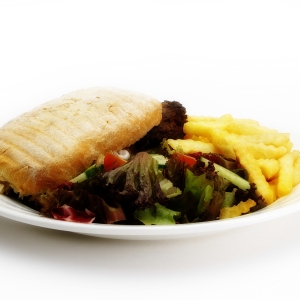 A beefburger and chips with a green salad