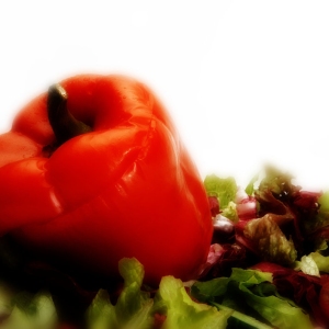 A stuffed red pepper with a green salad, macro view