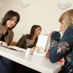 A group of girls or young women having lunch in a café or restaurant, or bar