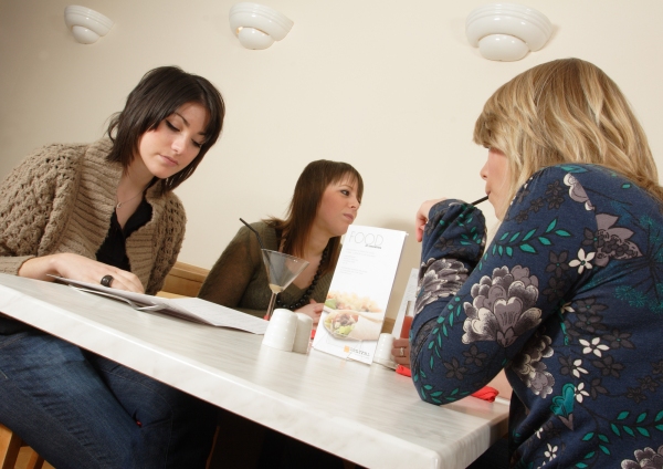 A group of girls or young women having lunch in a café or restaurant, or bar