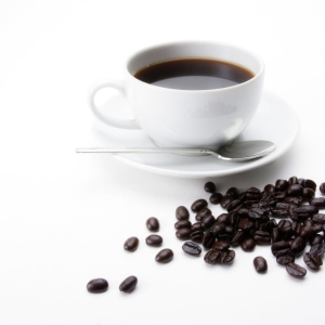 A cup of fresh coffee with some coffee beans