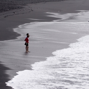 Holidaymaker wading in the surf on a black beach in Tenerife