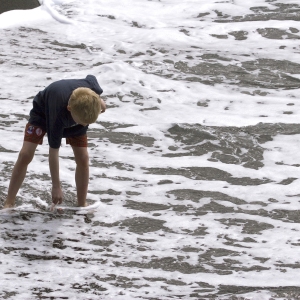 A young boy on holiday playing in the surf on a black beach in Tenerife