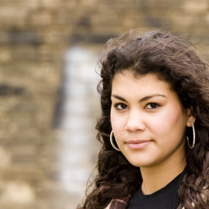 A mixed race girl looking wistfully at the camera in an urban setting.