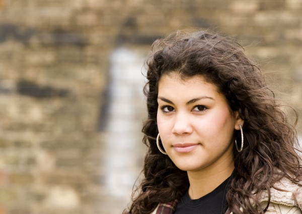 A mixed race girl looking wistfully at the camera in an urban setting.