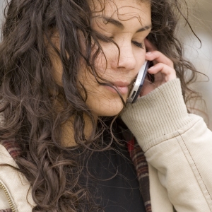 A mixed race teenage girl talking on the phone with her eyes closed