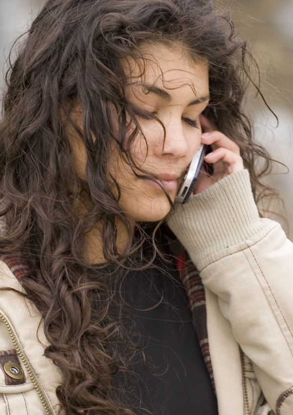 A mixed race teenage girl talking on the phone with her eyes closed