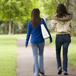 Two girls walking and talking in the park