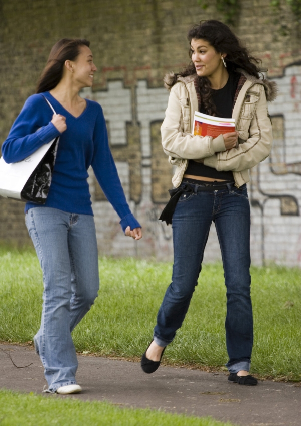 Two teenage girls walking home and chatting in a friendly manner