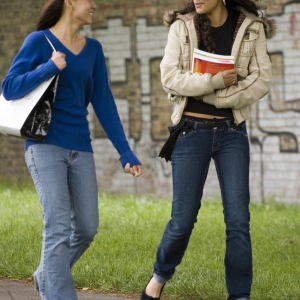 Two teenage girls walking home and chatting in a friendly manner