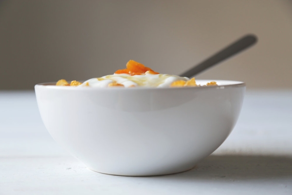 Cornflakes in a bowl with yogurt and honey.