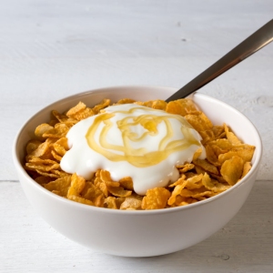 Cornflakes in a bowl with yogurt and honey.