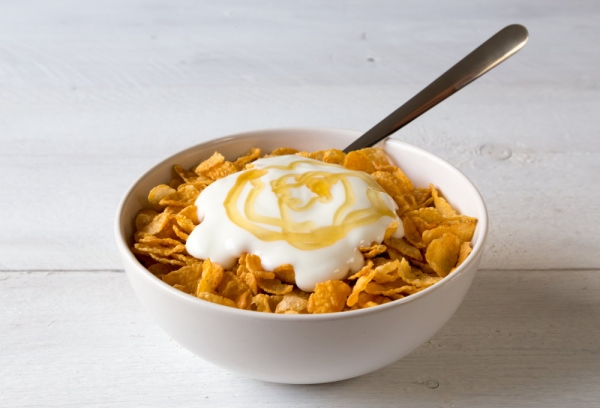 Cornflakes in a bowl with yogurt and honey.