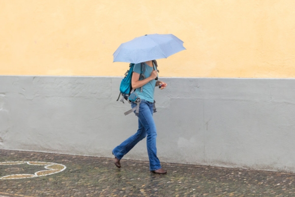 Girl walking with umbrella on rainy day in town